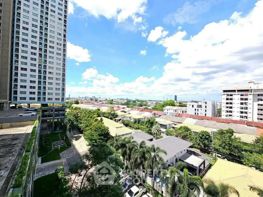 Stunning cityscape view from high-rise building with lush greenery and clear blue sky.