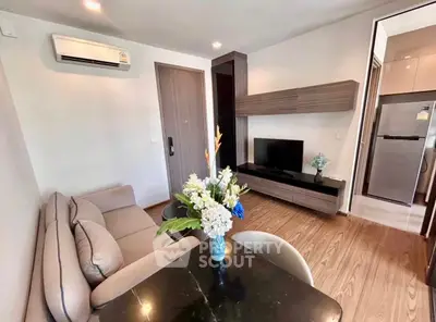 Modern living room with stylish furniture and open kitchen layout, featuring a cozy sofa and elegant decor.