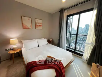 Modern bedroom with city view, featuring cozy decor and large window for natural light.