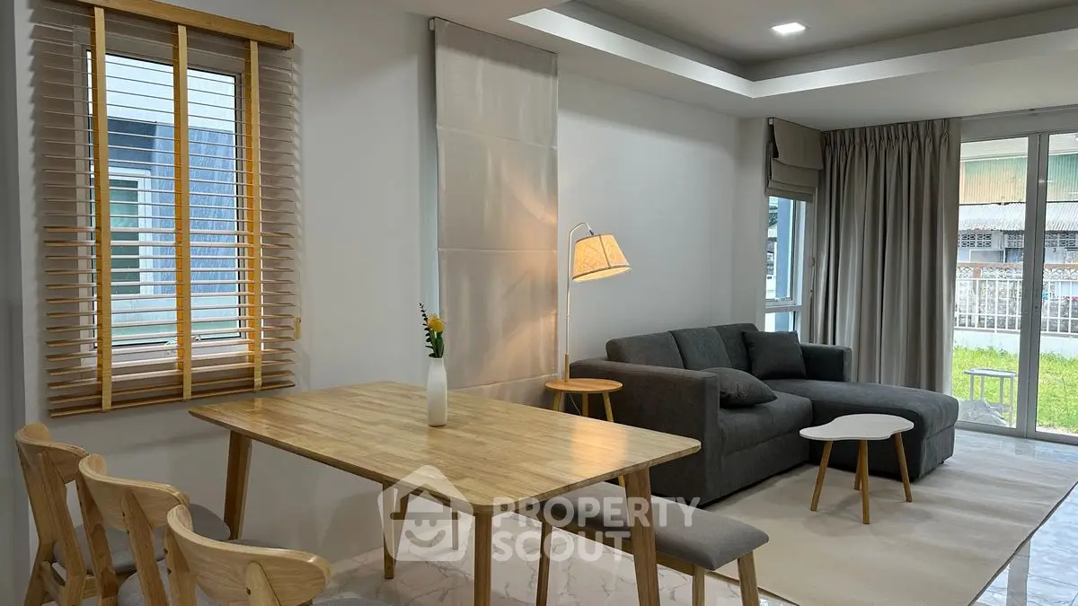 Modern living room with cozy sofa, wooden dining set, and large window view.