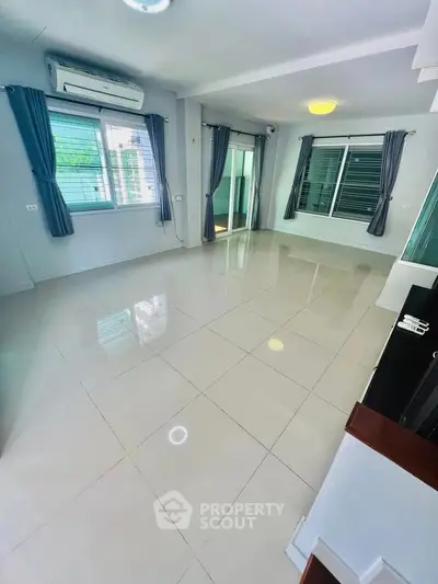 Spacious empty living room with large windows and tiled flooring