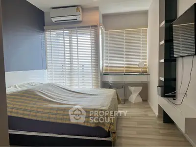 Modern bedroom with stylish decor and natural light, featuring a cozy bed and sleek furnishings.