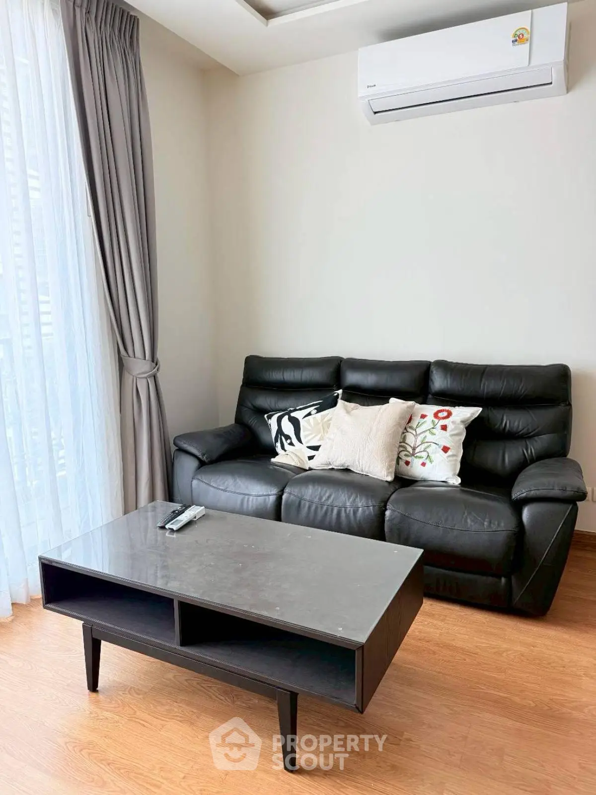 Modern living room with black leather sofa and sleek coffee table, featuring elegant decor and natural light.