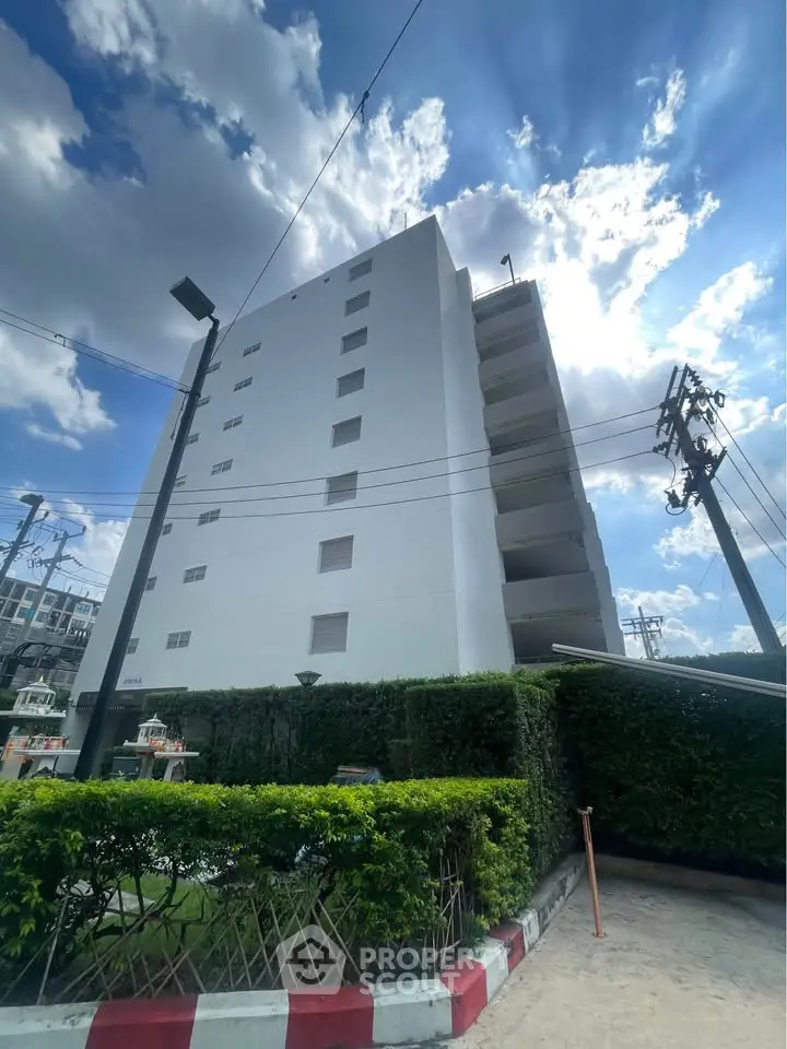 Modern white apartment building with lush greenery and clear blue sky