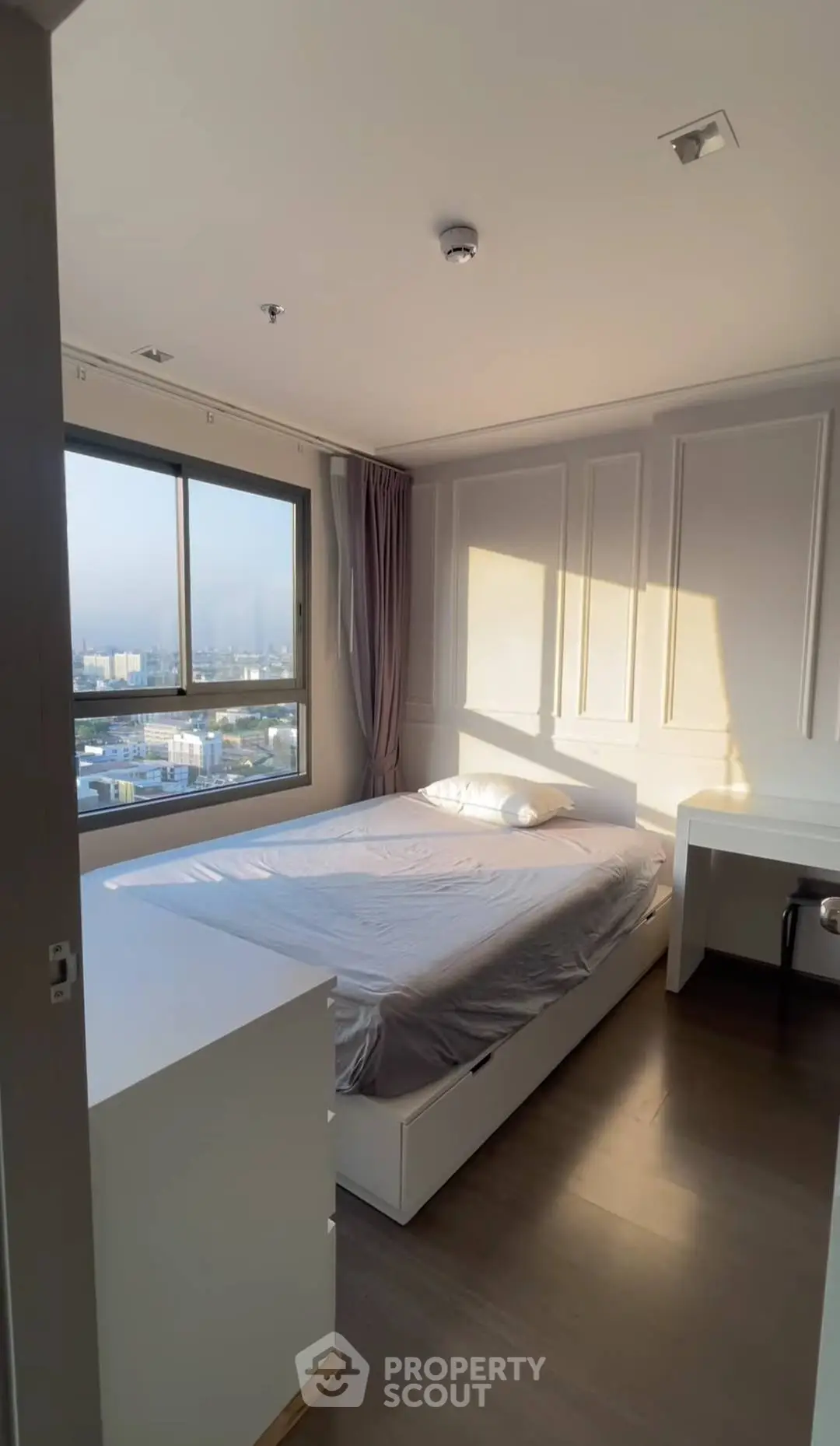 Modern bedroom with large window offering stunning city view