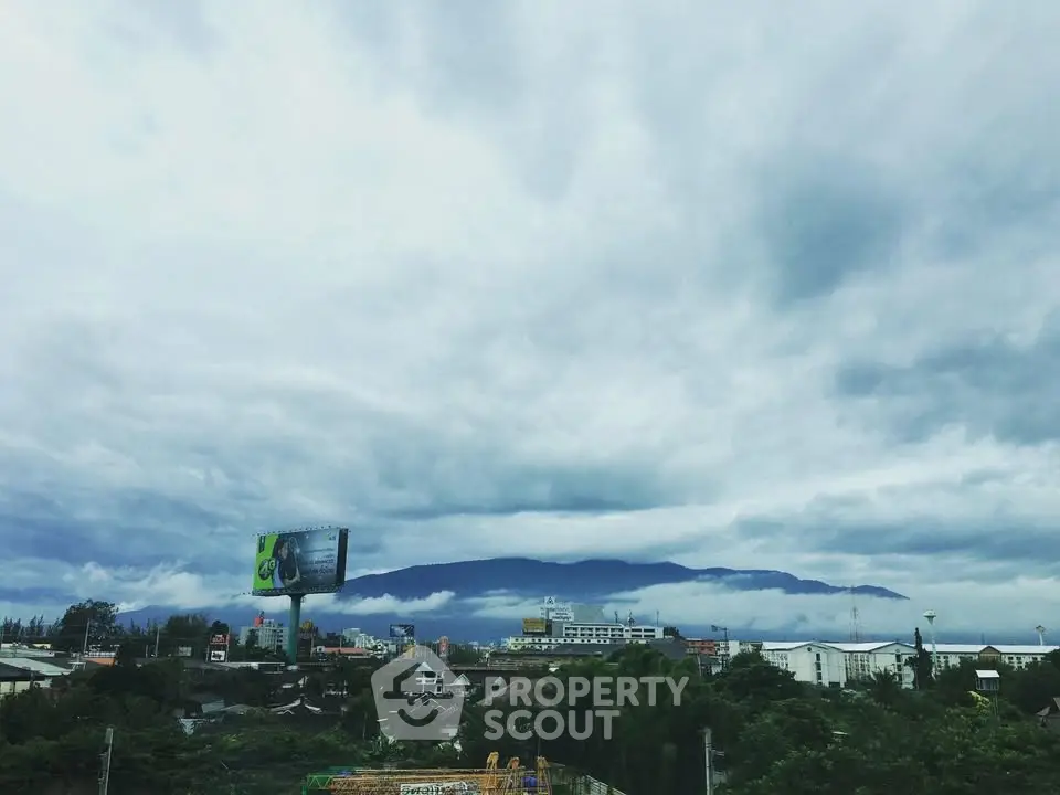 Scenic cityscape with mountain backdrop and cloudy sky, perfect for urban living.
