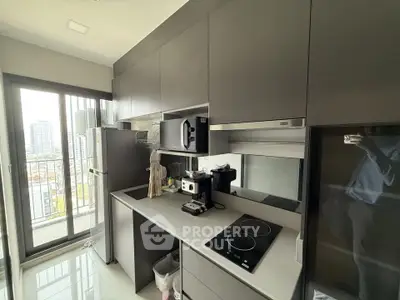 Modern kitchen with sleek cabinetry and appliances, featuring a balcony view.