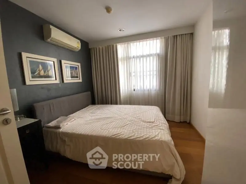 Cozy bedroom with modern decor and natural light, featuring a comfortable bed and stylish artwork.