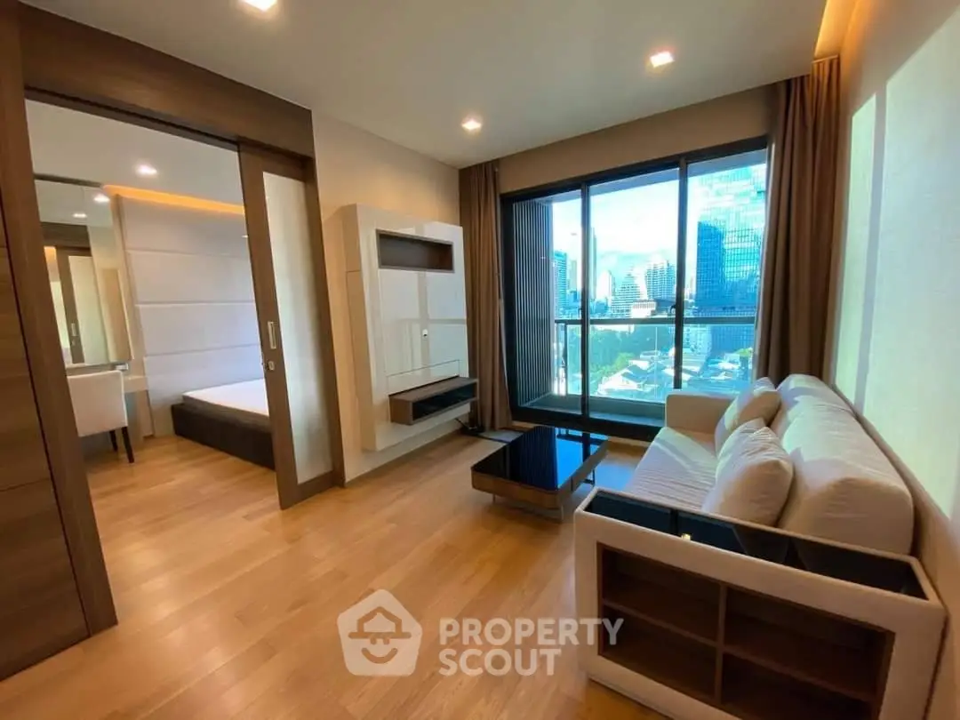 Modern living room with city view, featuring sleek furniture and wooden flooring in a high-rise apartment.