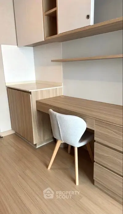 Modern study area with wooden desk and chair, built-in shelves, and storage cabinets.