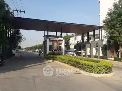 Gated community entrance with security booth and lush greenery