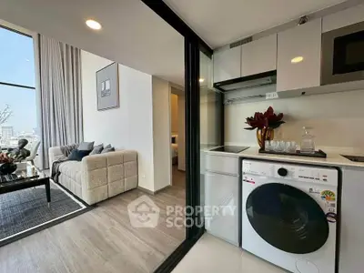 Modern apartment with open layout, featuring a cozy living room and sleek kitchen with washing machine.