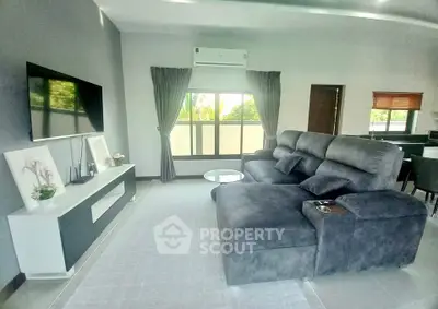 Spacious modern living room with plush gray sofa and sleek entertainment center, perfect for relaxation.