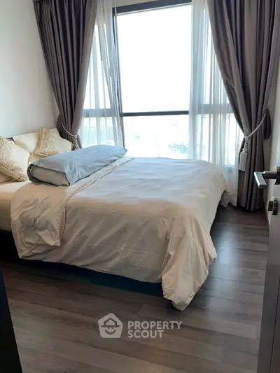 Cozy bedroom with large window and elegant curtains, perfect for relaxation.
