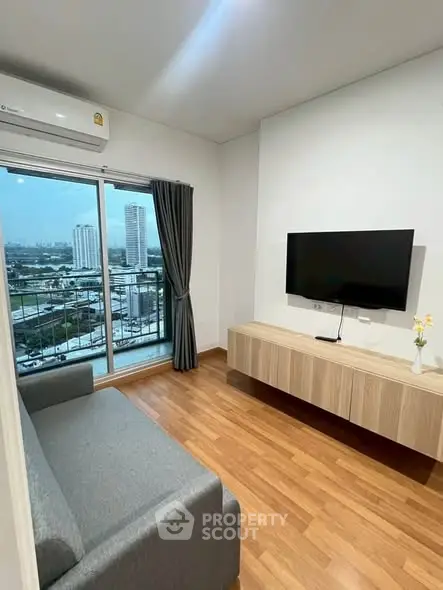 Modern living room with city view, sleek TV setup, and cozy sofa in a high-rise apartment.