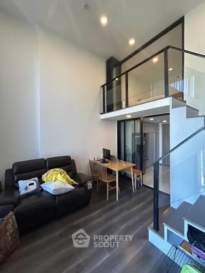 Modern loft-style living room with high ceiling and sleek staircase