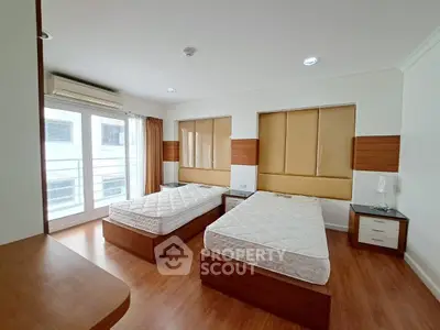 Spacious bedroom with twin beds and large windows in modern apartment