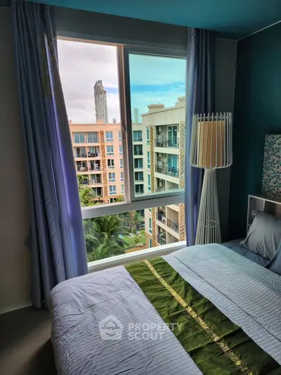 Cozy bedroom with a view of modern high-rise buildings through a large window, featuring elegant curtains and a stylish lamp.