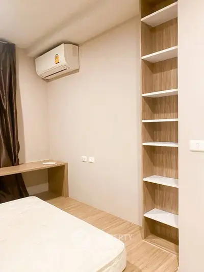 Modern bedroom with built-in shelves and air conditioning, featuring minimalist design and neutral tones.