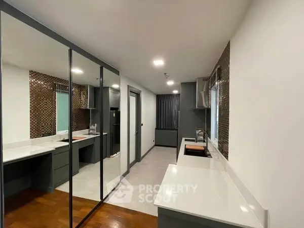 Modern kitchen with sleek cabinetry and mirrored wall for spacious feel