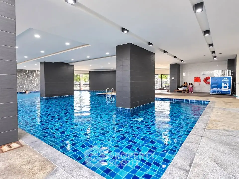 Luxurious indoor swimming pool with modern design and vibrant blue tiles in a high-end residential complex.