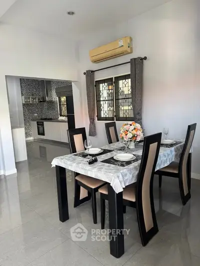 Elegant dining area with modern kitchen in open layout, featuring stylish decor and ample natural light.