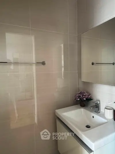 Modern bathroom with sleek sink and mirror, featuring elegant tile design and subtle decor.