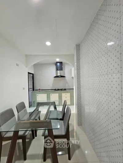 Modern kitchen with glass dining table and sleek cabinetry in open layout design.