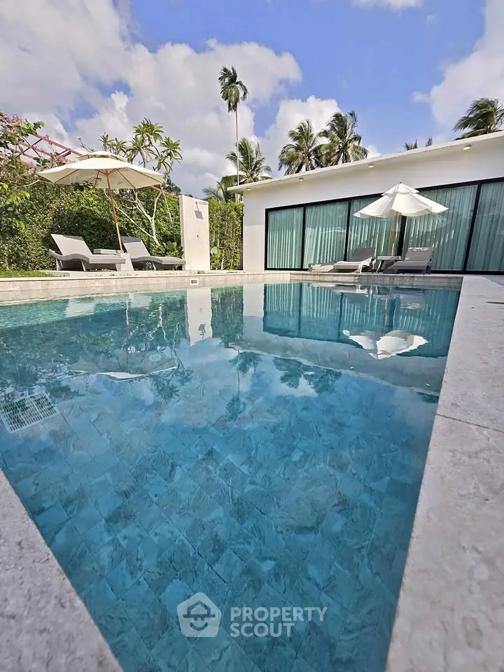 Luxurious villa with private pool and sun loungers, surrounded by tropical greenery.