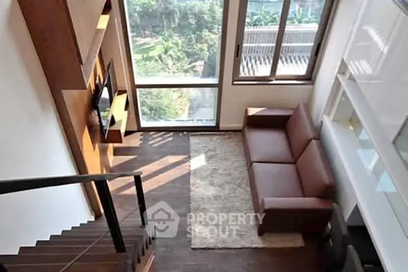 Modern living room with high ceiling and large windows offering a scenic view.