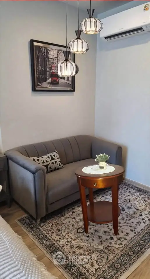 Charming living room with cozy gray sofa, elegant pendant lights, and stylish decor.