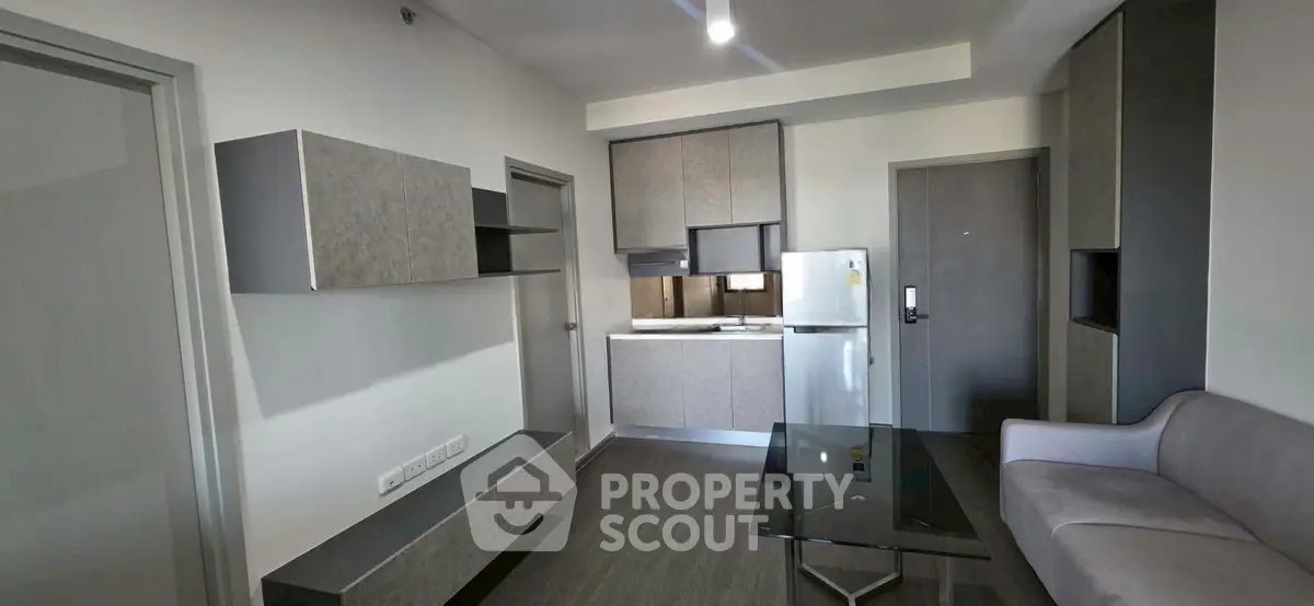 Modern living room with sleek furniture and compact kitchen area in a stylish apartment.