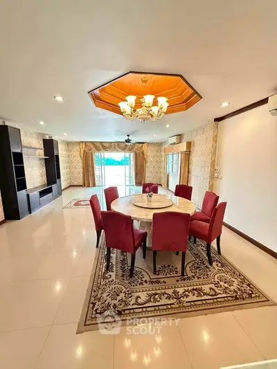 Spacious living room with elegant dining area and chandelier, featuring large windows and stylish decor.