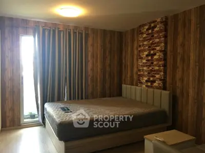 Cozy bedroom with stylish wood paneling and brick accent wall, featuring a comfortable bed and natural light.