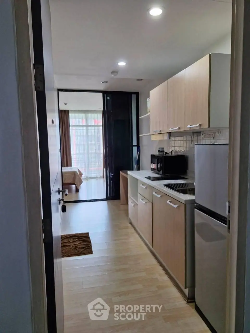 Modern apartment with sleek kitchen and cozy bedroom view, perfect for urban living.