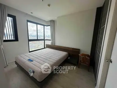 Spacious bedroom with large windows offering stunning city views in modern apartment.
