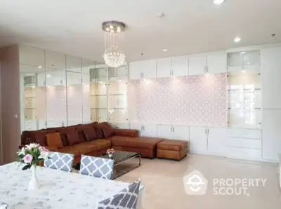 Spacious living room with elegant white cabinetry and modern lighting, featuring a large brown sectional sofa and glossy tiled flooring.