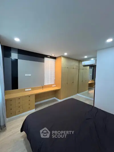 Spacious modern bedroom with built-in wooden wardrobe and sleek design