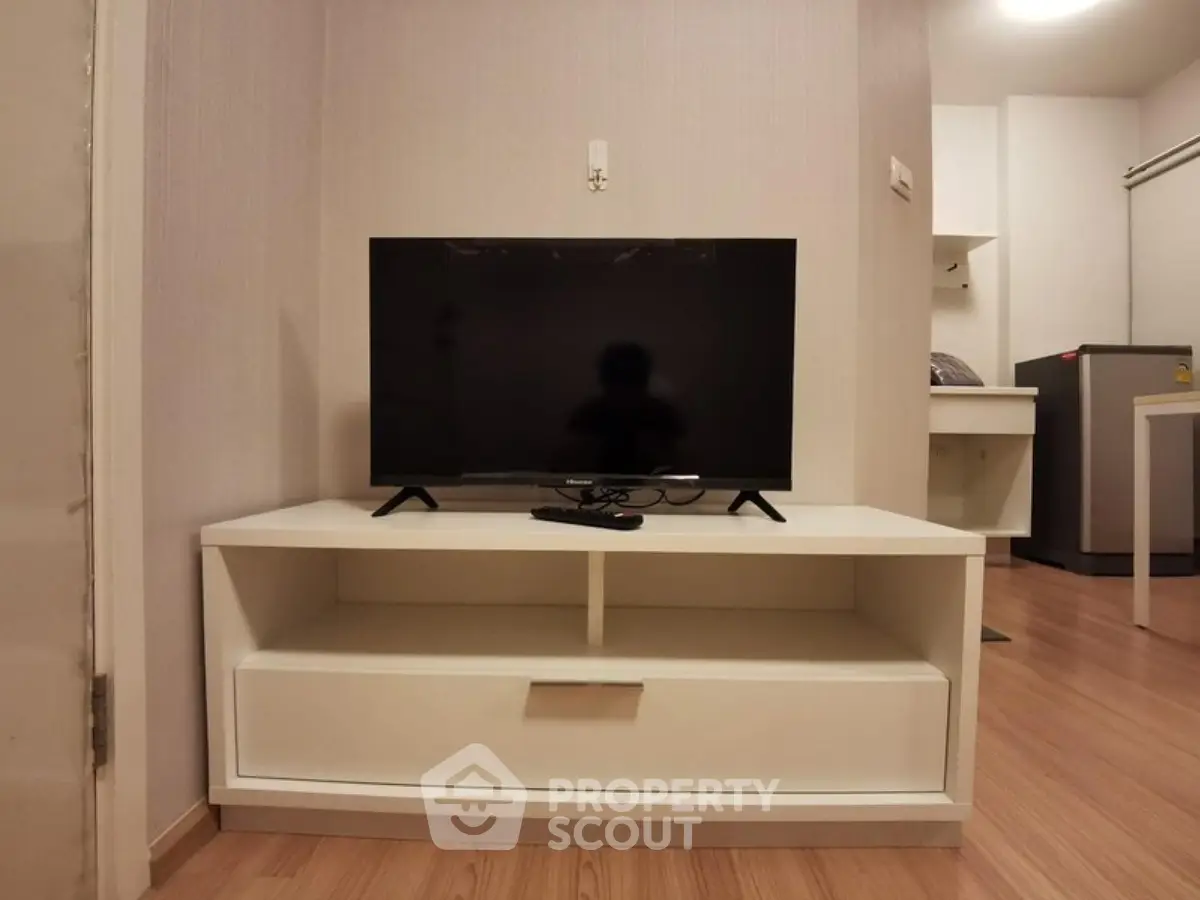 Modern living room with sleek TV stand and flat-screen TV, showcasing minimalist design and wooden flooring.