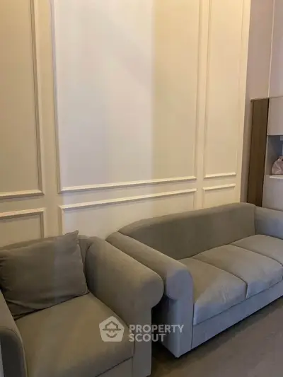 Elegant living room with stylish gray sofas and classic wall paneling