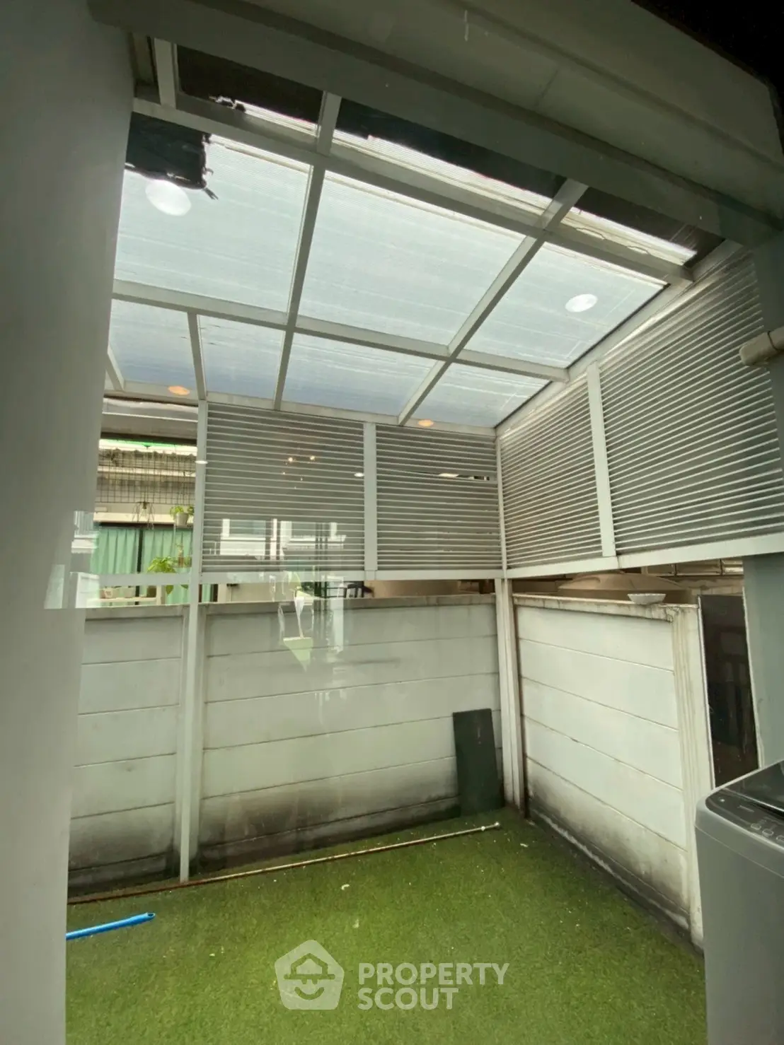 Modern enclosed outdoor space with artificial grass and skylight roof
