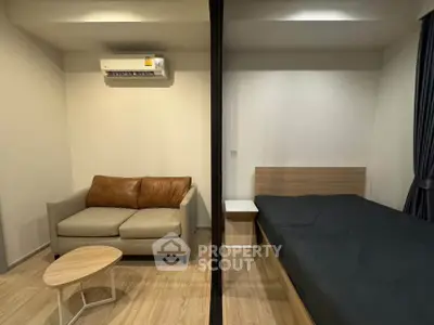 Modern studio apartment with cozy living area and comfortable bed, featuring sleek wooden flooring and air conditioning.