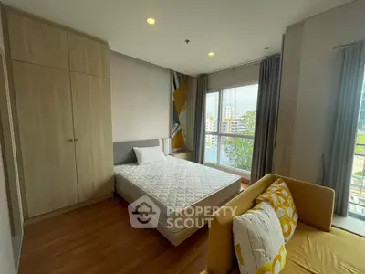 Spacious bedroom with modern decor and large windows offering city views.