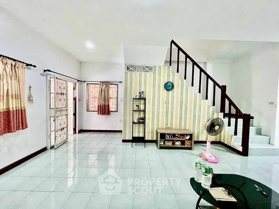 Spacious living room with staircase and natural light, perfect for family gatherings.