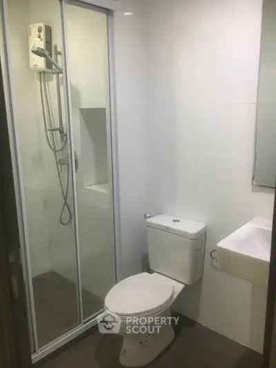 Modern bathroom with shower enclosure and sleek white fixtures.