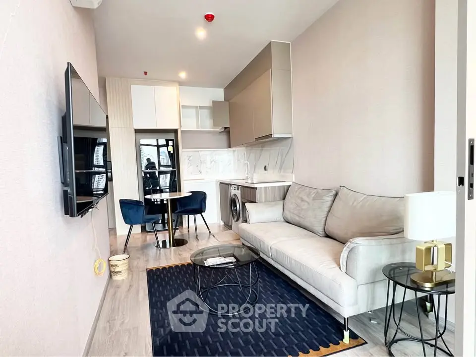Modern living room with sleek kitchen, cozy sofa, and stylish decor in a contemporary apartment.