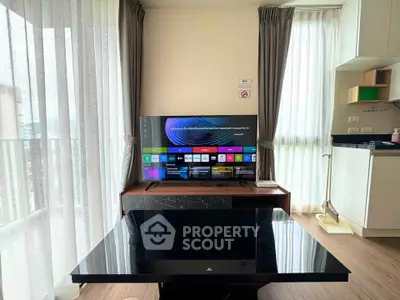 Modern living room with sleek TV setup and open kitchen layout, featuring floor-to-ceiling windows for natural light.