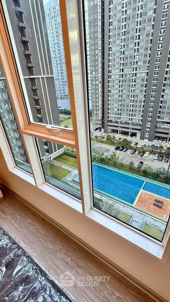 High-rise apartment view with pool and cityscape from window.