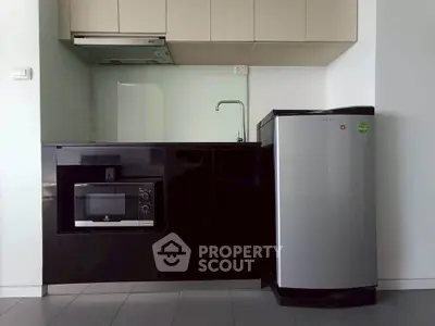 Modern compact kitchen with sleek black cabinetry and stainless steel appliances.