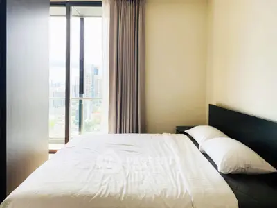 Modern bedroom with large window offering stunning city view, featuring a comfortable bed and elegant decor.